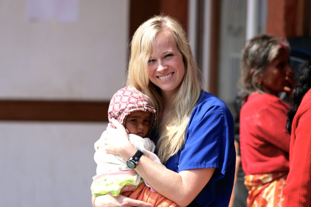 RVU student smiling while holding an infant on an international externship trip