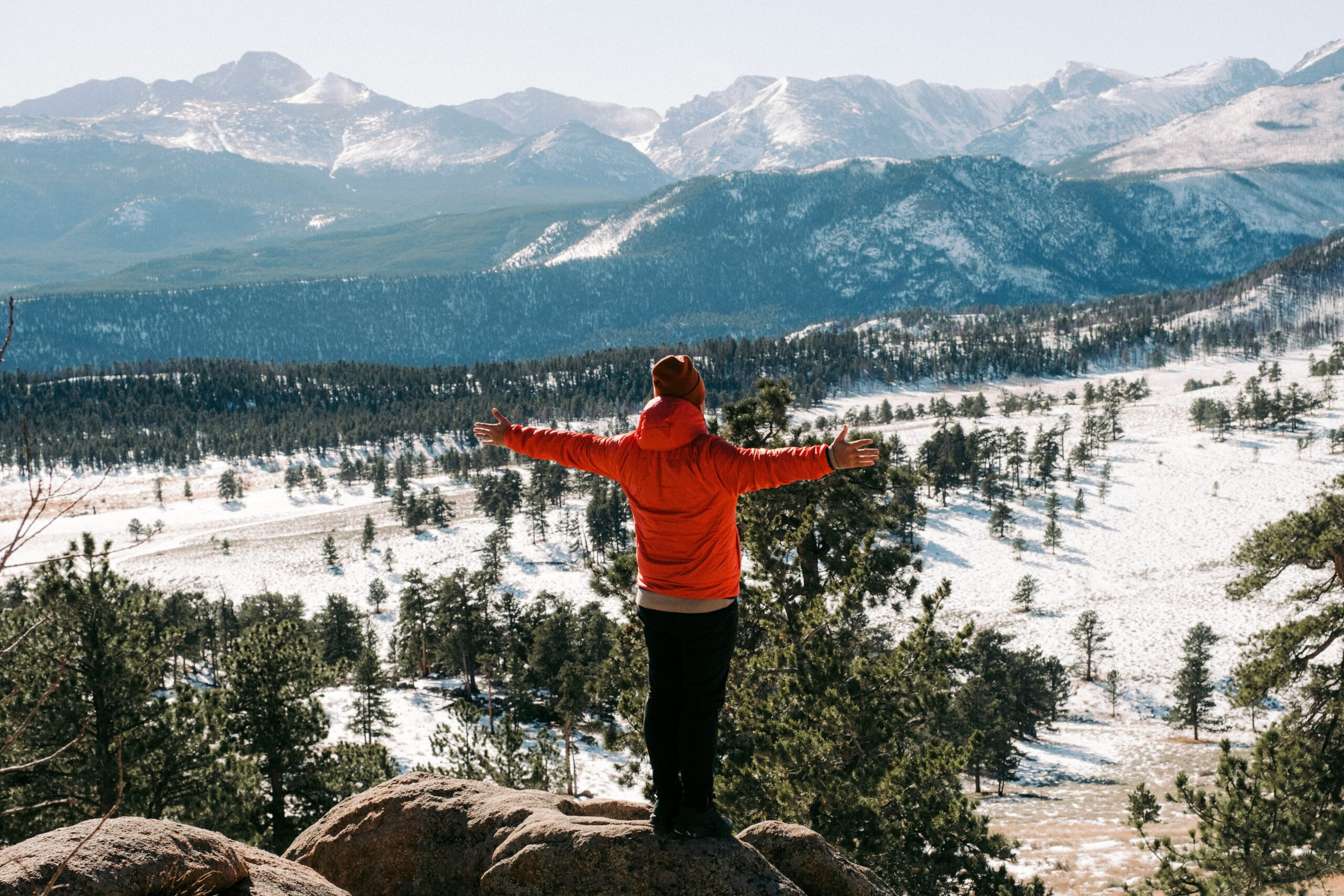 Person standing on rock looking over snowy landscape. 