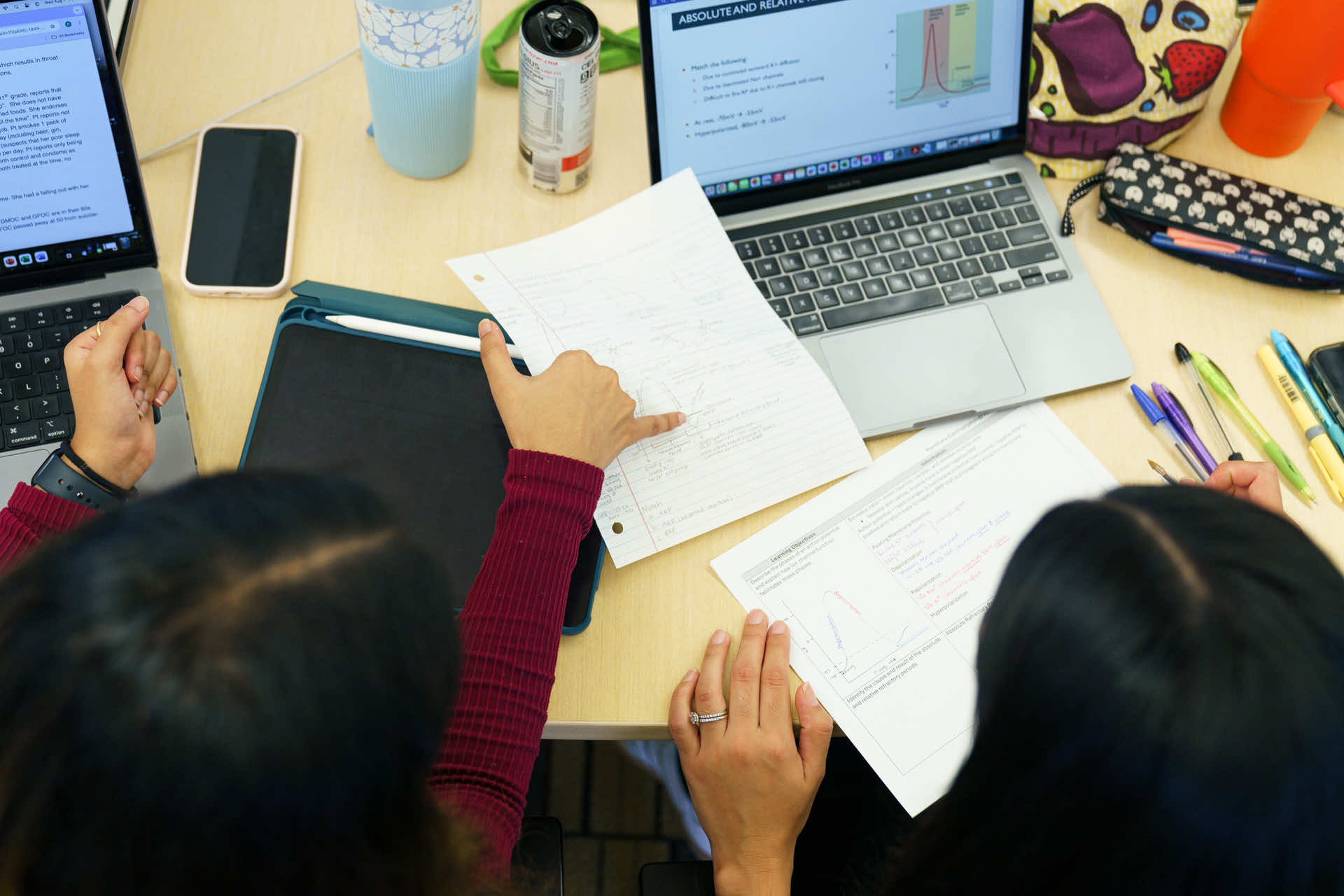 Students working at desk looking at paper.