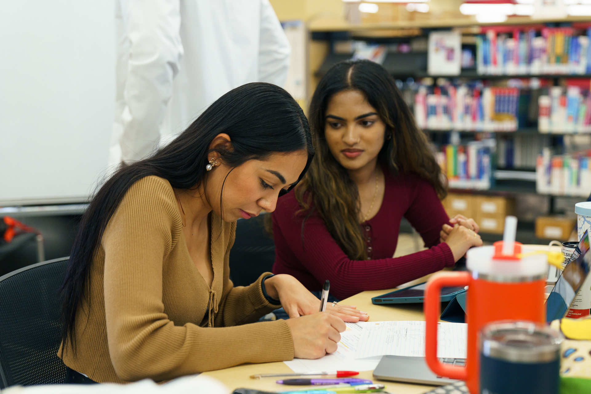 2 students sitting at the table chatting.