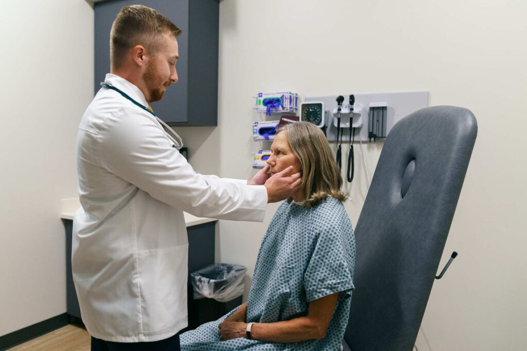 Doctor touching womans ears on Montana Campus. 