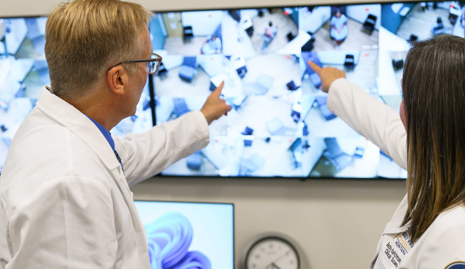 Teacher and med student pointing at a screen