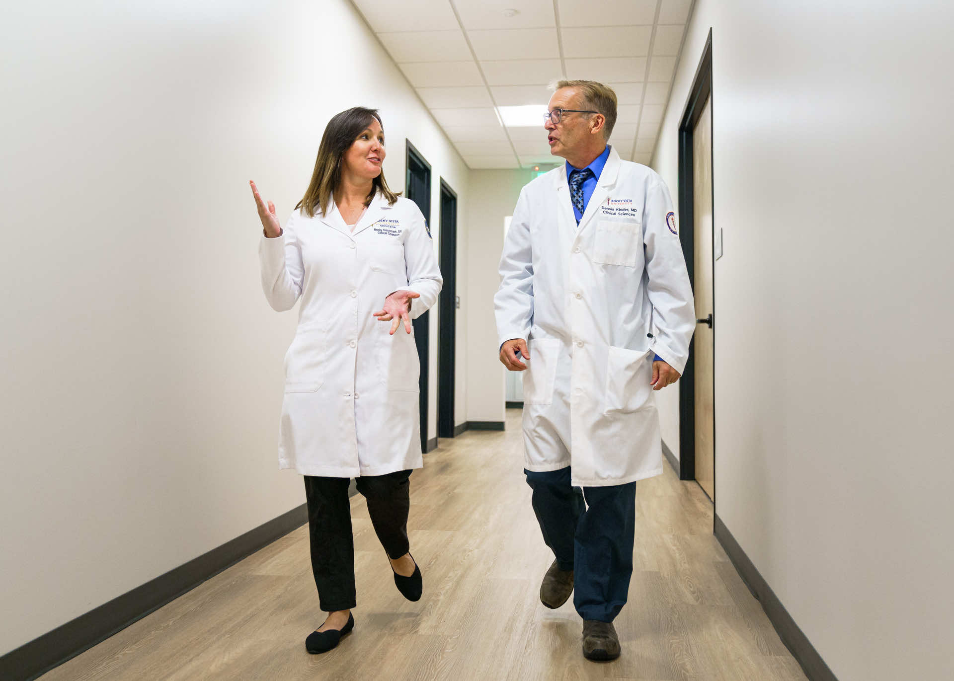 Man and woman in doctors coats walking down a hallway