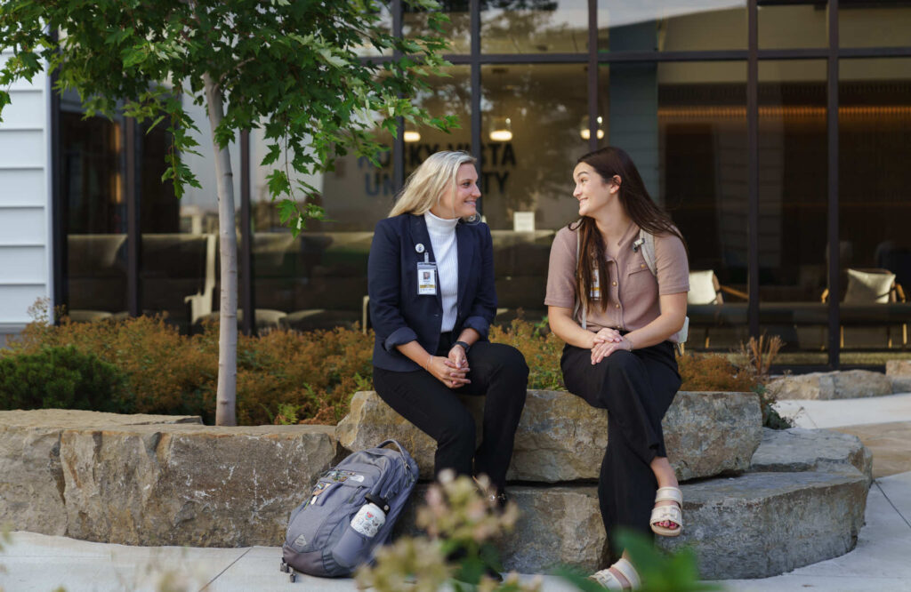 Woman and student talking outside on a rock