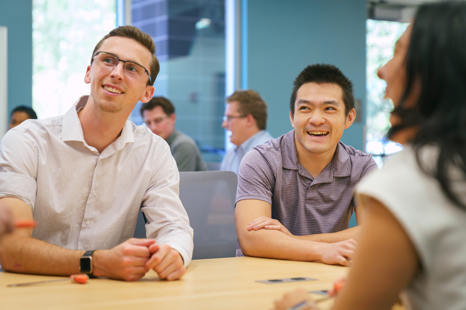 3 students sitting around a table looking up something out of the image