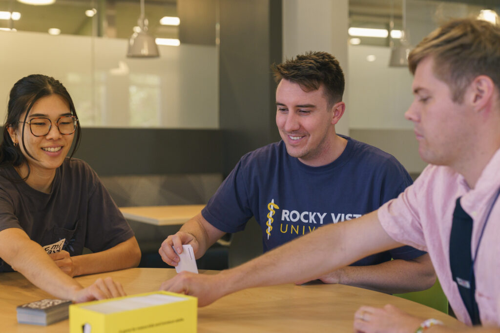 Students at a table smiling on the Utah Campus. 