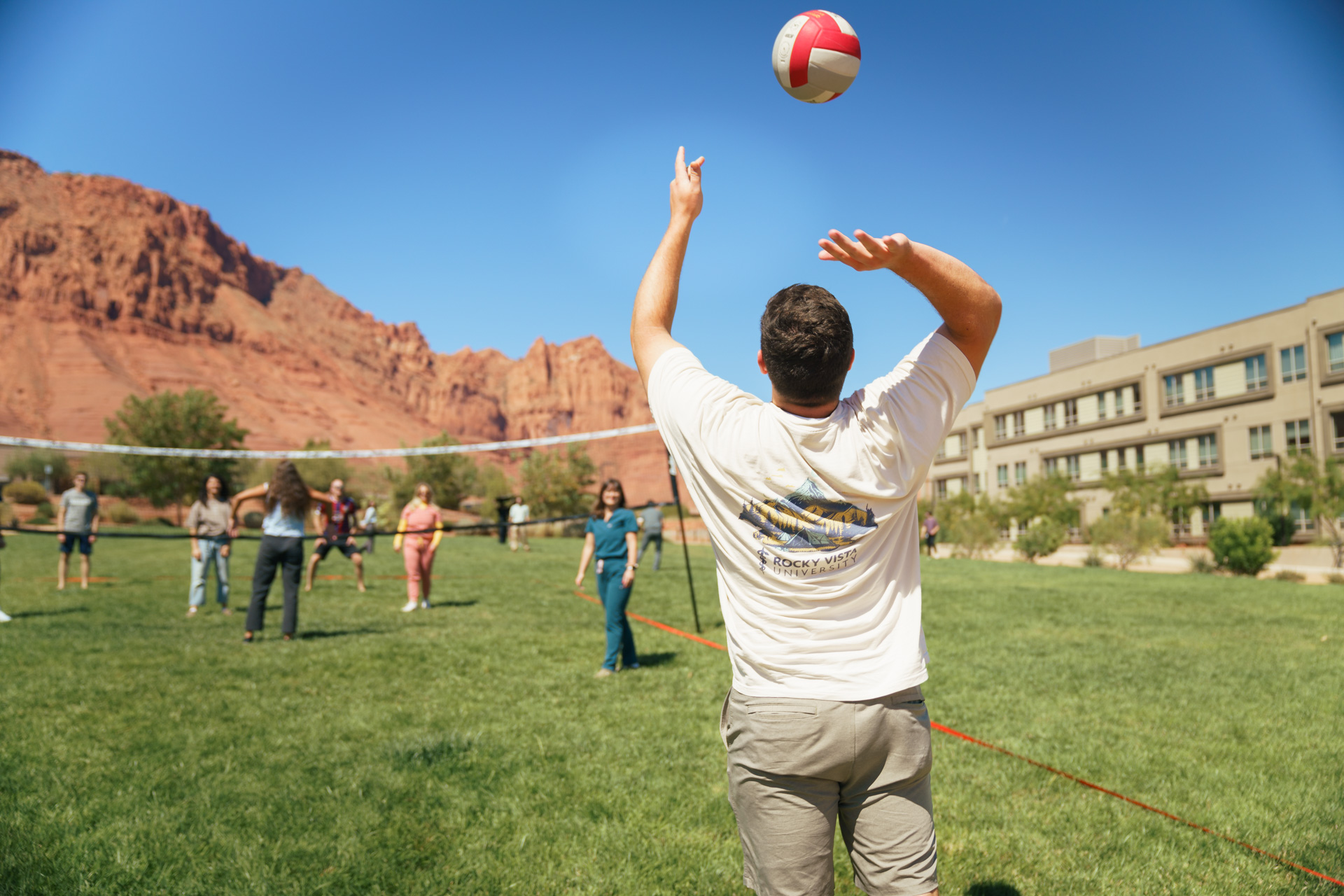 Students playing volleyball outdoors. 